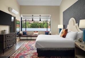 A modern hotel room with a large bed, a desk, and a view of the outdoors.