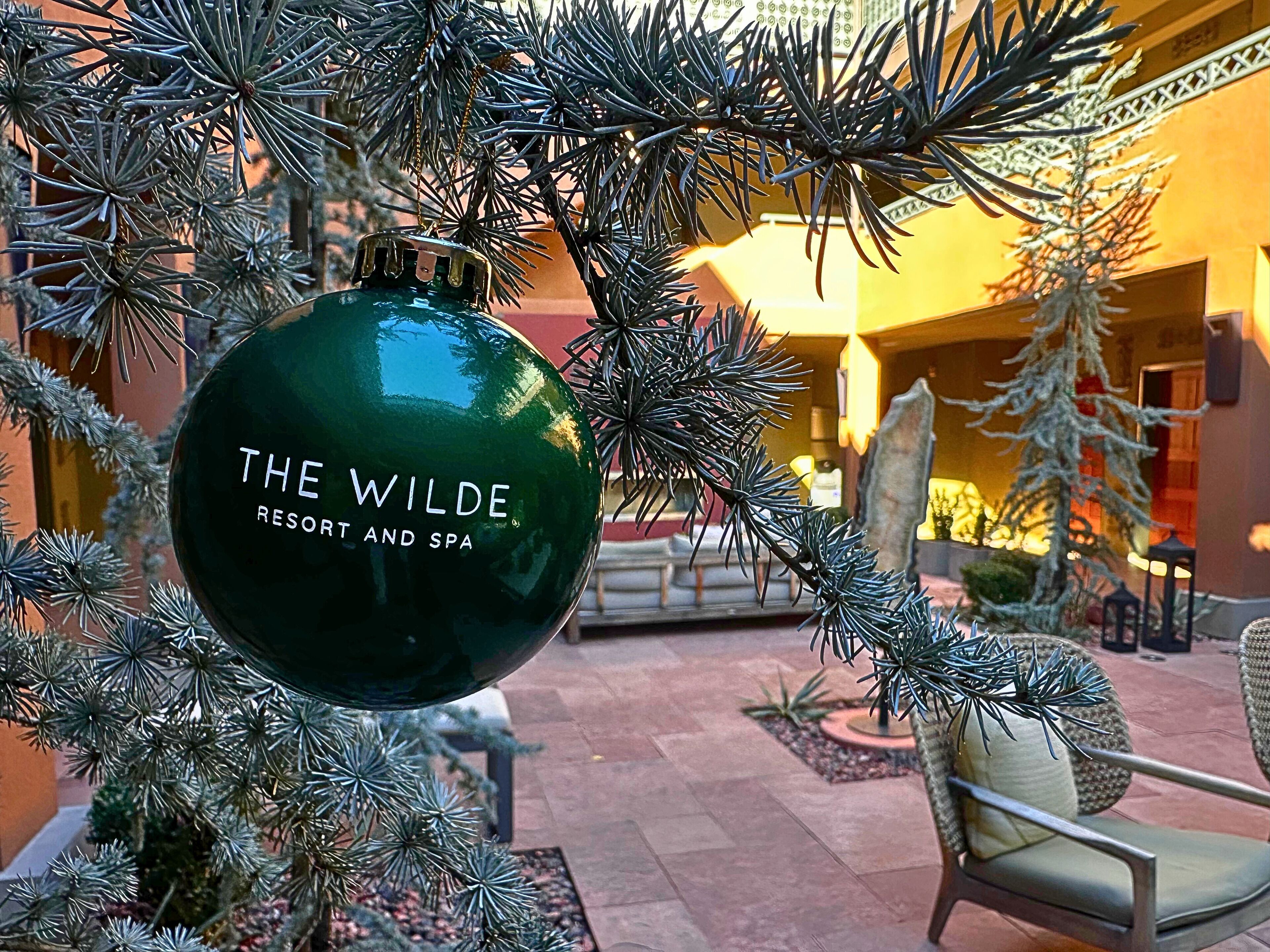 Un adorno navideño con el texto "THE WILDE RESORT AND SPA" colgado de un árbol.