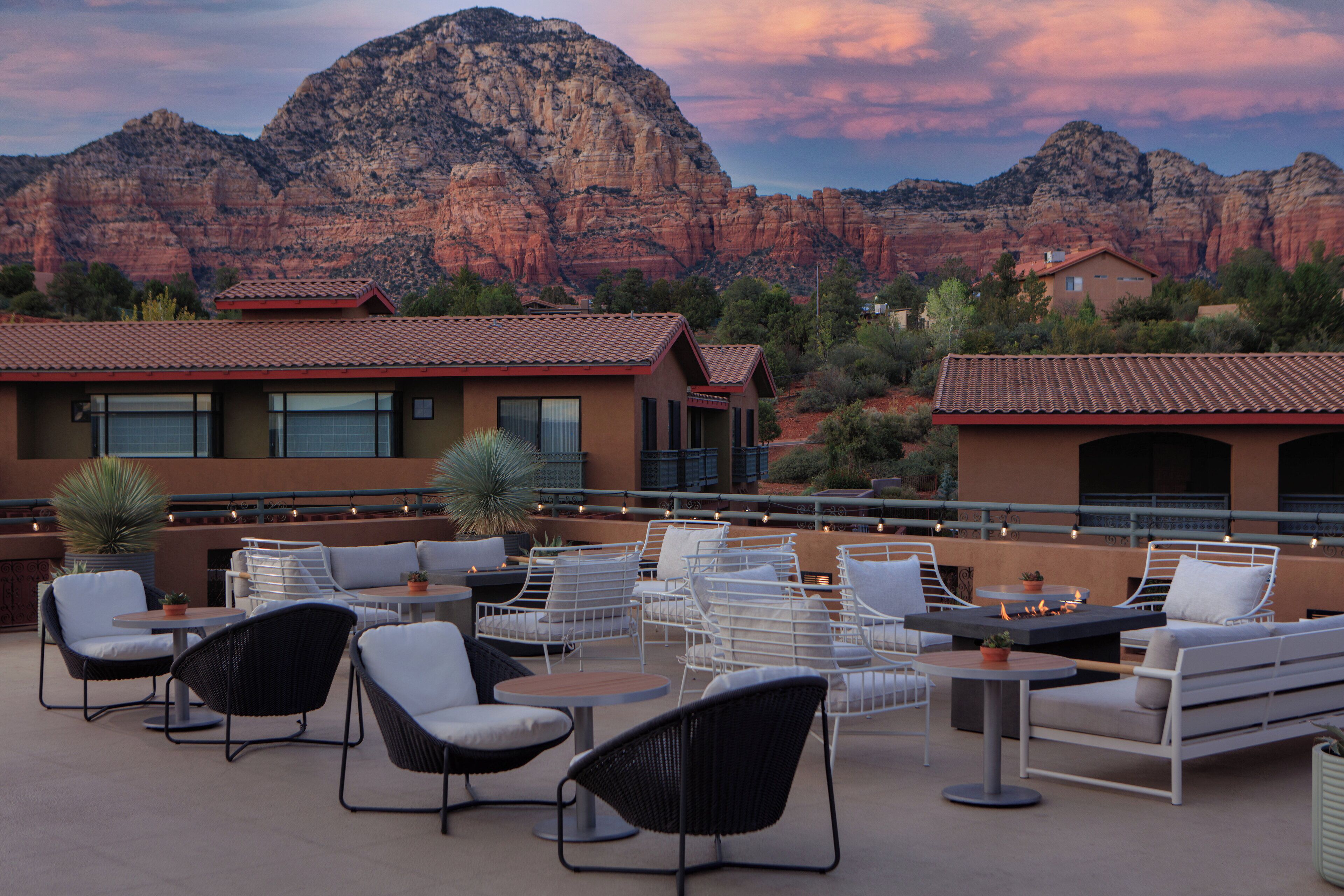 An outdoor patio with seating and tables, overlooking a mountainous landscape.