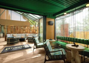 A modern lobby with a green ceiling, a wooden partition labeled "Lobby," and a seating area with sofas and chairs.
