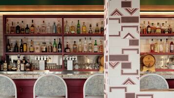 A bar area with multiple shelves of bottles, bar stools, and a patterned wall.