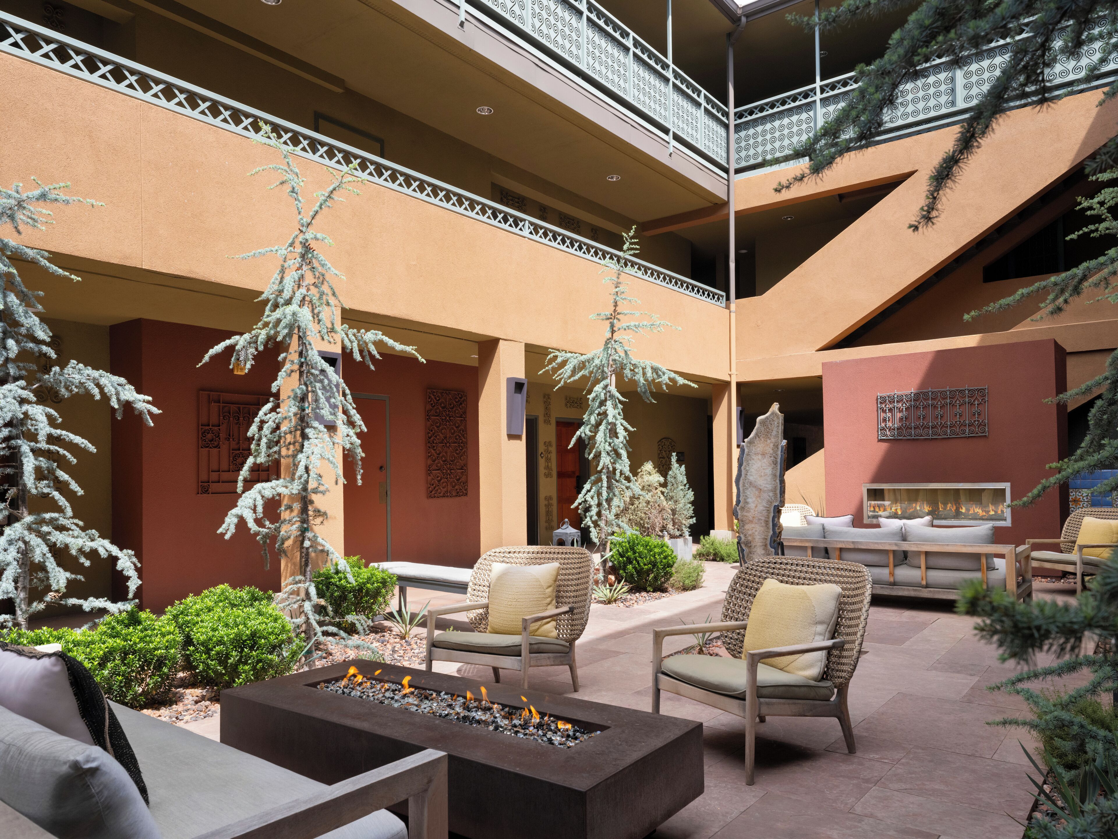 A spacious outdoor seating area with fire pits, wicker furniture, and decorative plants.