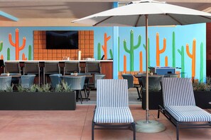 An outdoor seating area with striped lounge chairs, a table with chairs, and a large umbrella.