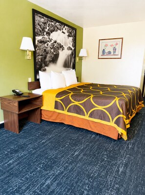 A hotel room with a bed, two bedside lamps, a telephone, a desk, and a framed picture on the wall. - Super 8 by Wyndham Rawlins (Rawlins)