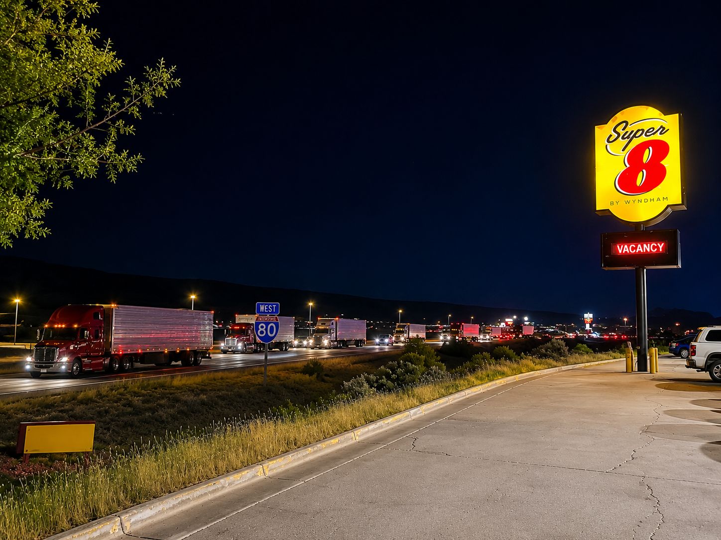 A highway scene with a large 'Super 8' sign indicating a motel, a 'VACANCY' sign, and multiple trucks on the road.