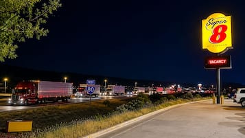 A highway scene with a large 'Super 8' sign indicating a motel, a 'VACANCY' sign, and multiple trucks on the road.