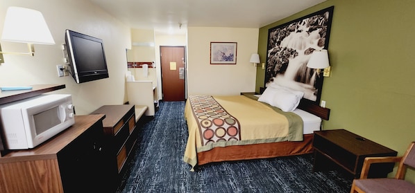 A hotel room with a bed, a desk with a computer, a TV, a bathroom, and a painting on the wall. - Super 8 by Wyndham Rawlins (Rawlins)