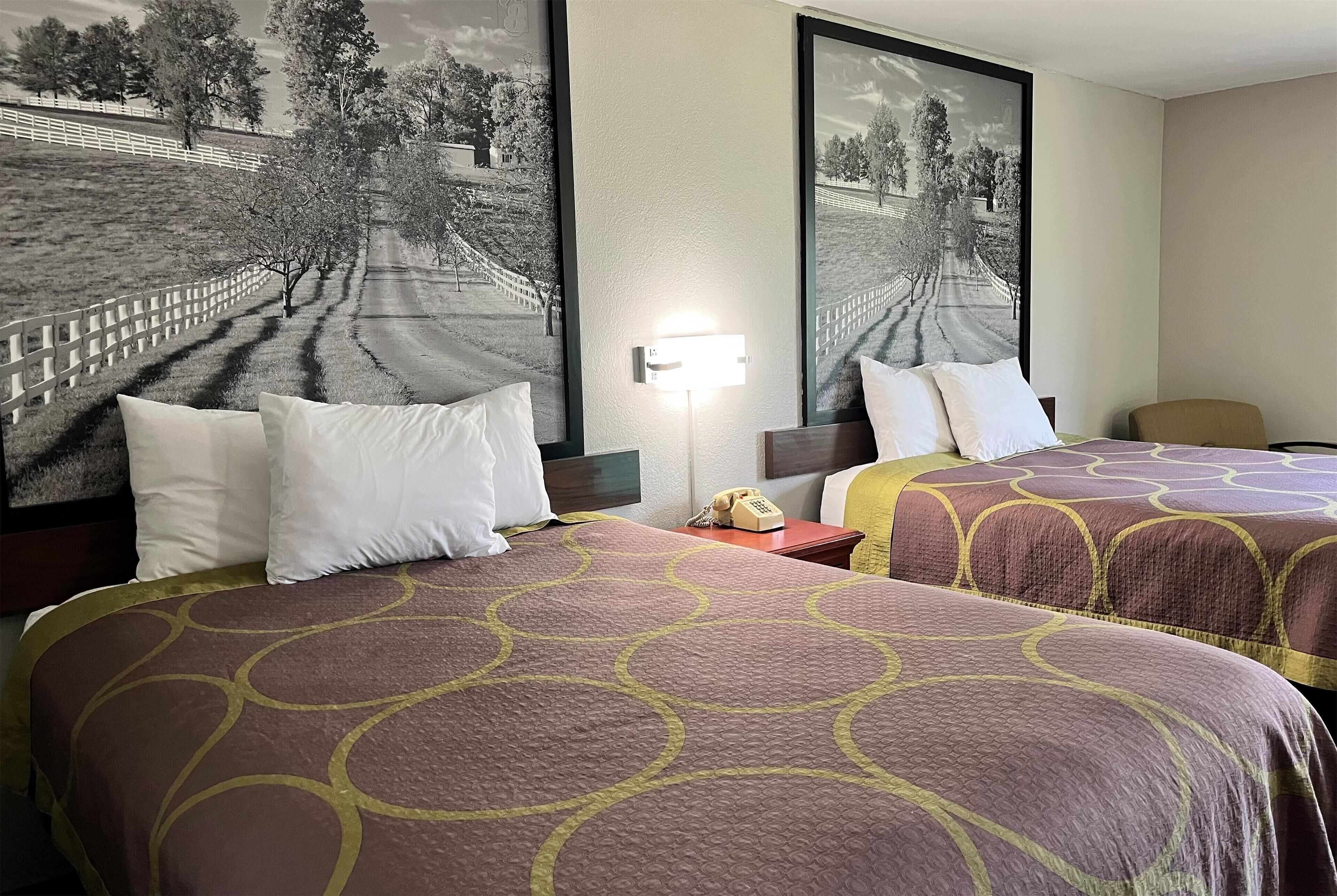Une chambre d’hôtel avec deux lits, une table de chevet avec un téléphone et une lampe fixée au mur.