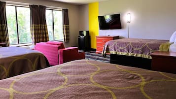 A hotel room with two beds, a TV, a dresser, and a window with curtains.