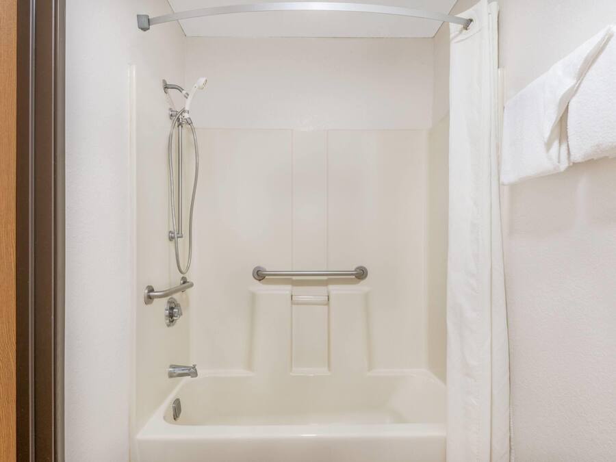 A bathroom with a bathtub, a shower, and a handrail.