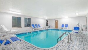 A swimming pool with blue tiles, white walls, and blue lounge chairs. - Super 8 by Wyndham Vincennes (Vincennes)