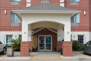 A brick building with a covered entrance, a parking lot, and a sign indicating handicapped parking.