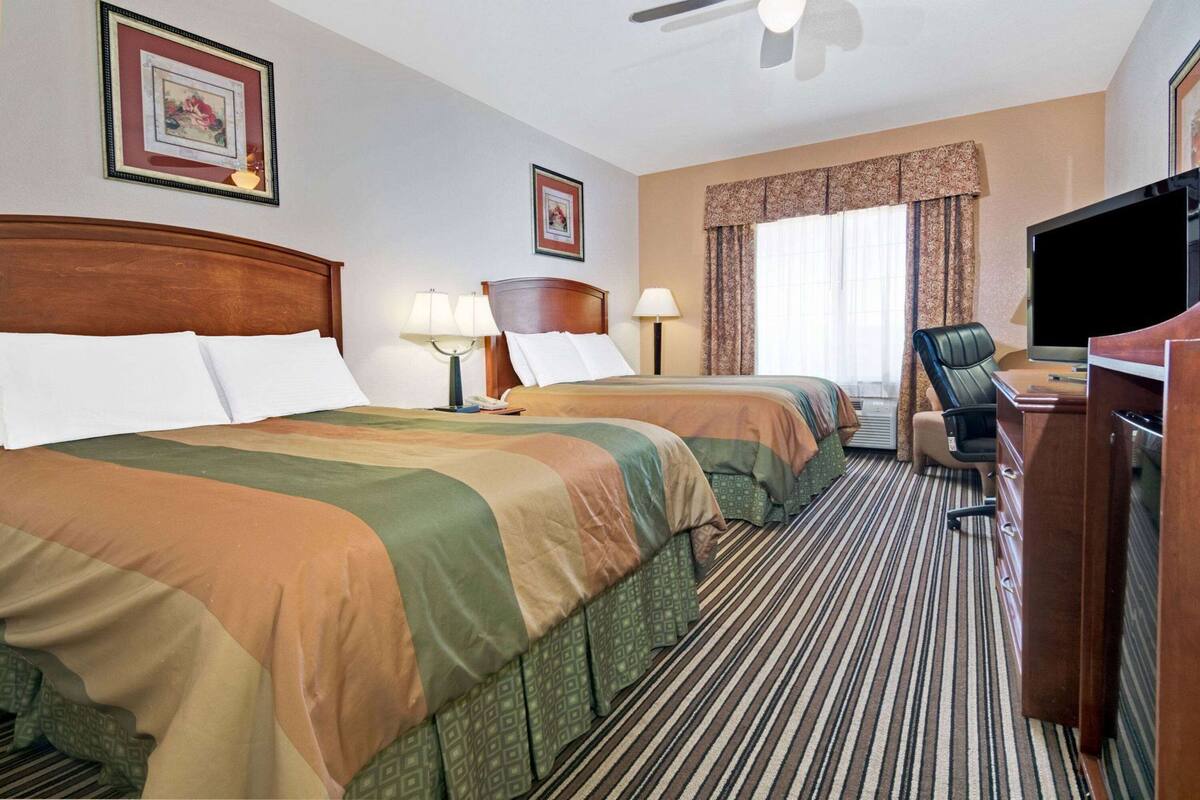 Una habitación de hotel con dos camas, un escritorio, un televisor y un ventilador de techo.