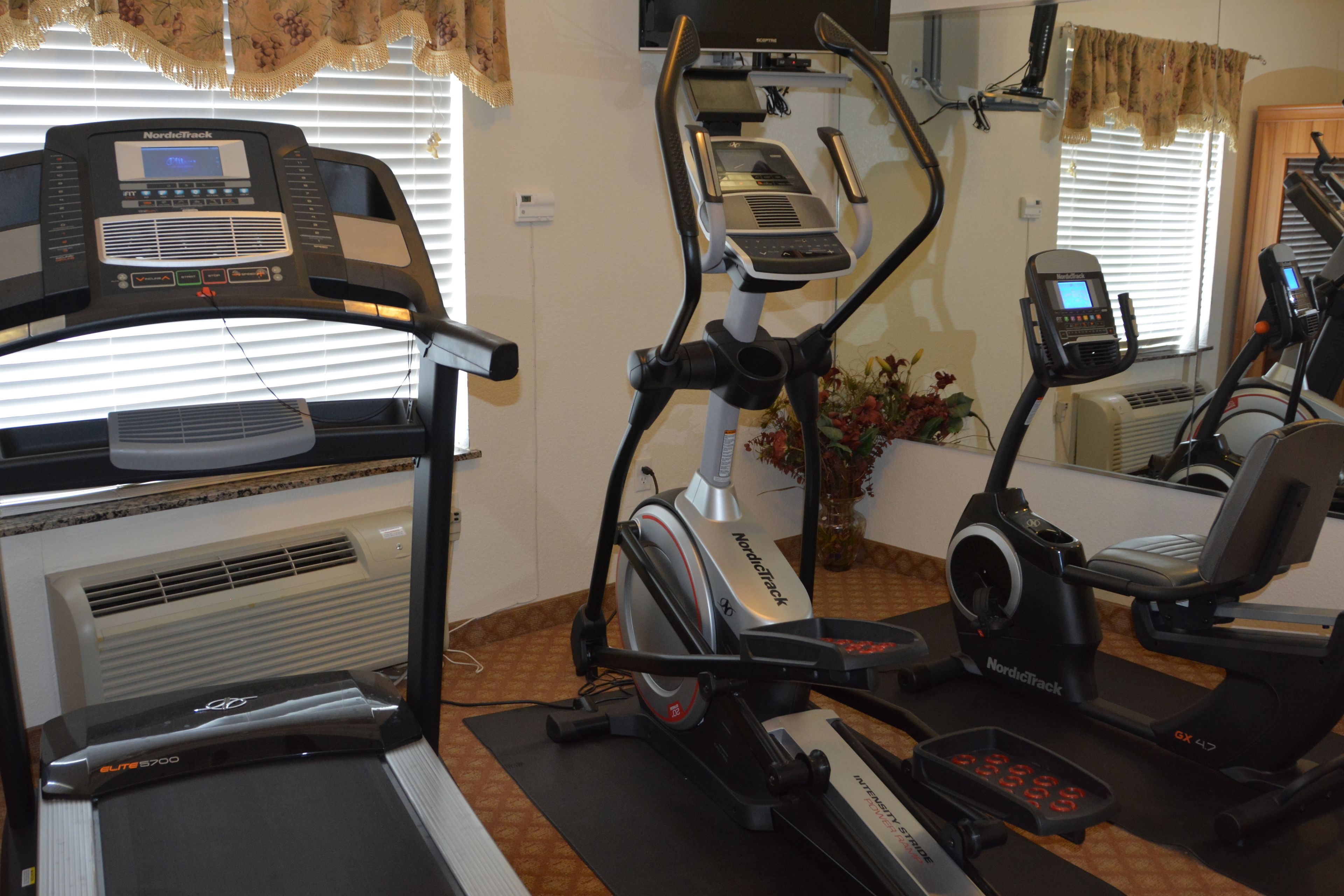 A home gym with a treadmill, elliptical, and stationary bike.