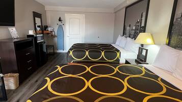 A hotel room with two beds, a desk, a chair, a mirror, a door, and a window with a cityscape view.