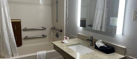 A modern bathroom with a bathtub, a sink, and a mirror.