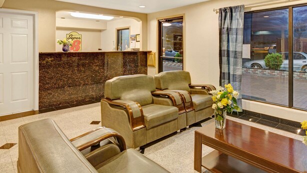 Eine Hotelhalle mit einer Rezeption, zwei Sofas, einem Couchtisch und einem großen Fenster mit Blick auf die Straße.