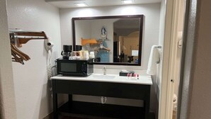 Ein kleines Badezimmer mit Waschbecken, Spiegel und einer Kaffeemaschine.