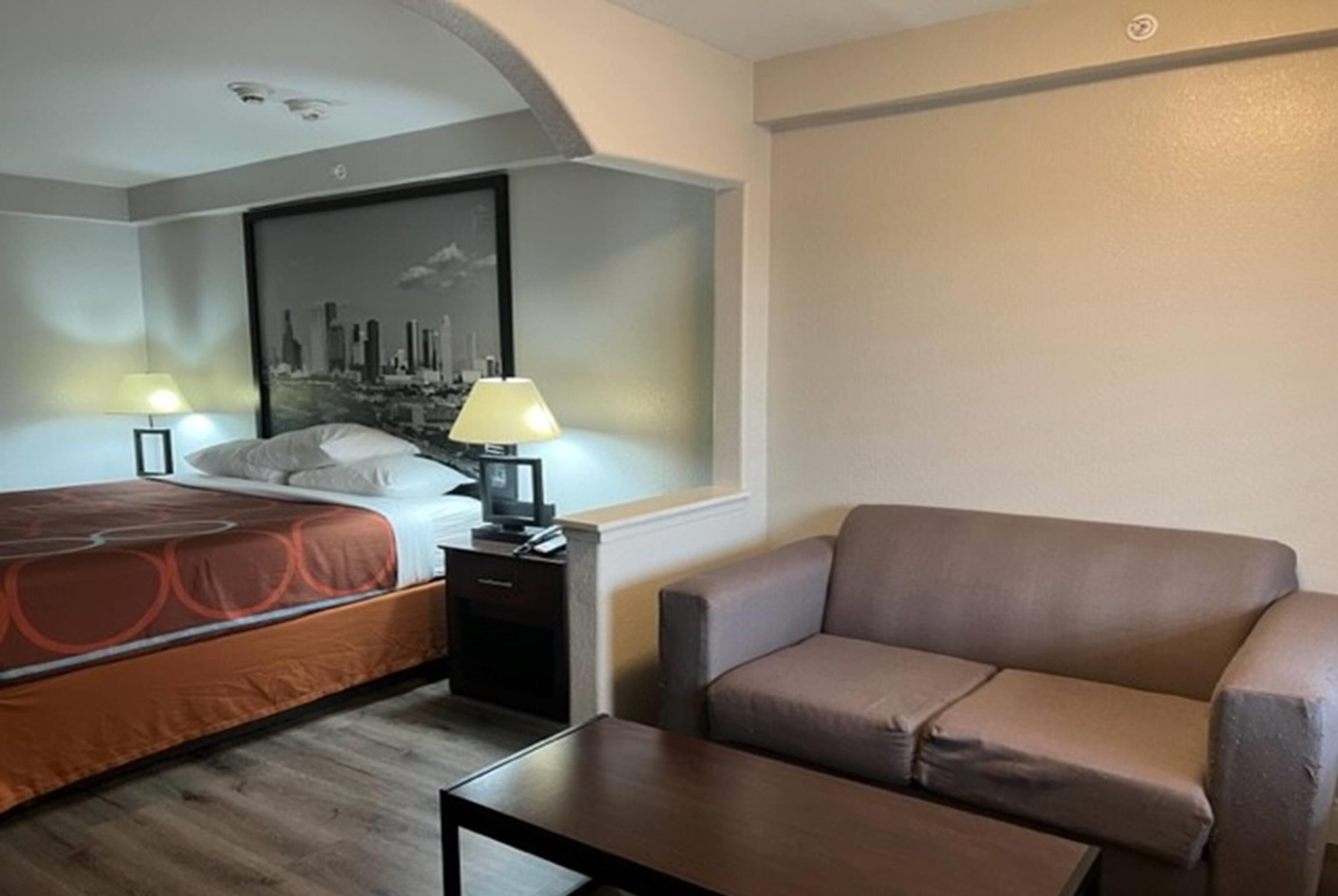 Een hotelkamer met een bed, een bureau, een stoel en uitzicht op de stad.