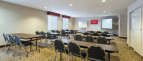 A conference room with tables, chairs, a projector screen, and a sign indicating free Wi-Fi availability.