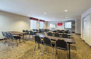 A conference room with tables, chairs, a projector screen, and a sign indicating free Wi-Fi availability.