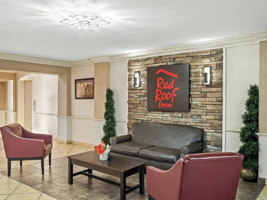 A lobby with a stone wall, a Red Roof Inn sign, leather seating, and a coffee table.