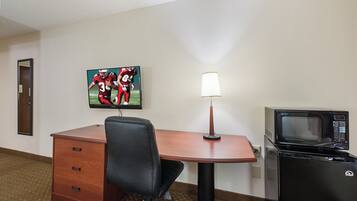 Habitación de hotel con escritorio, silla, lámpara y microondas.