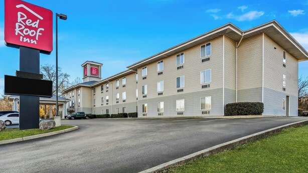 Un hôtel Red Roof Inn avec un bâtiment à deux étages, un parking et un ciel bleu dégagé.