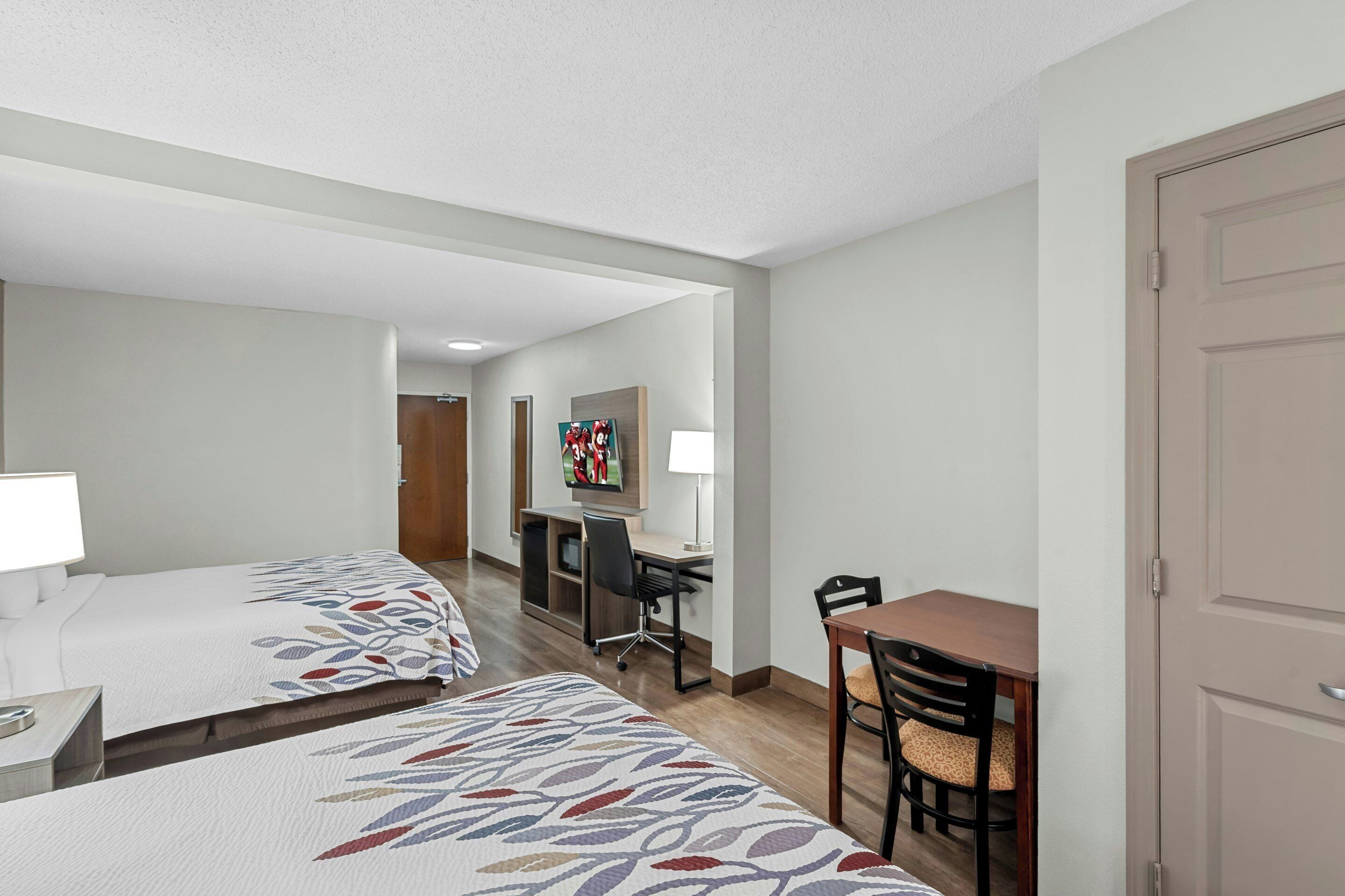 Habitación de hotel con dos camas, un escritorio, una silla y una mesa de comedor.