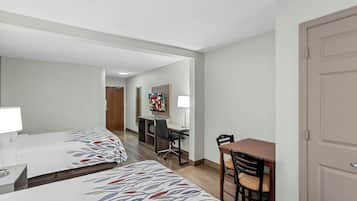Habitación de hotel con dos camas, un escritorio, una silla y una mesa de comedor.