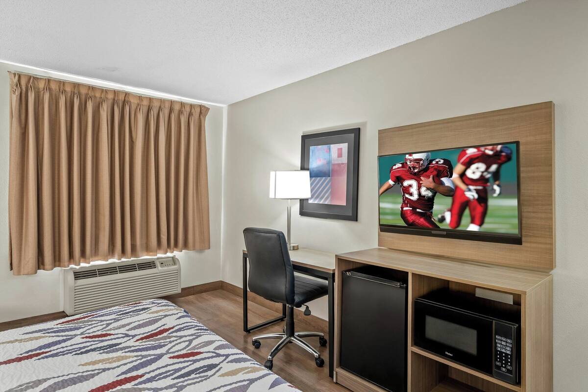 Een hotelkamer met een bed, een bureau, een televisie en een magnetron.