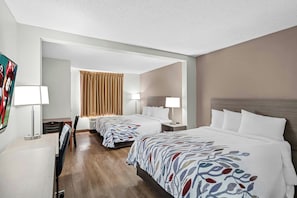 A hotel room with two beds, a desk, a chair, a TV, and a window with curtains.
