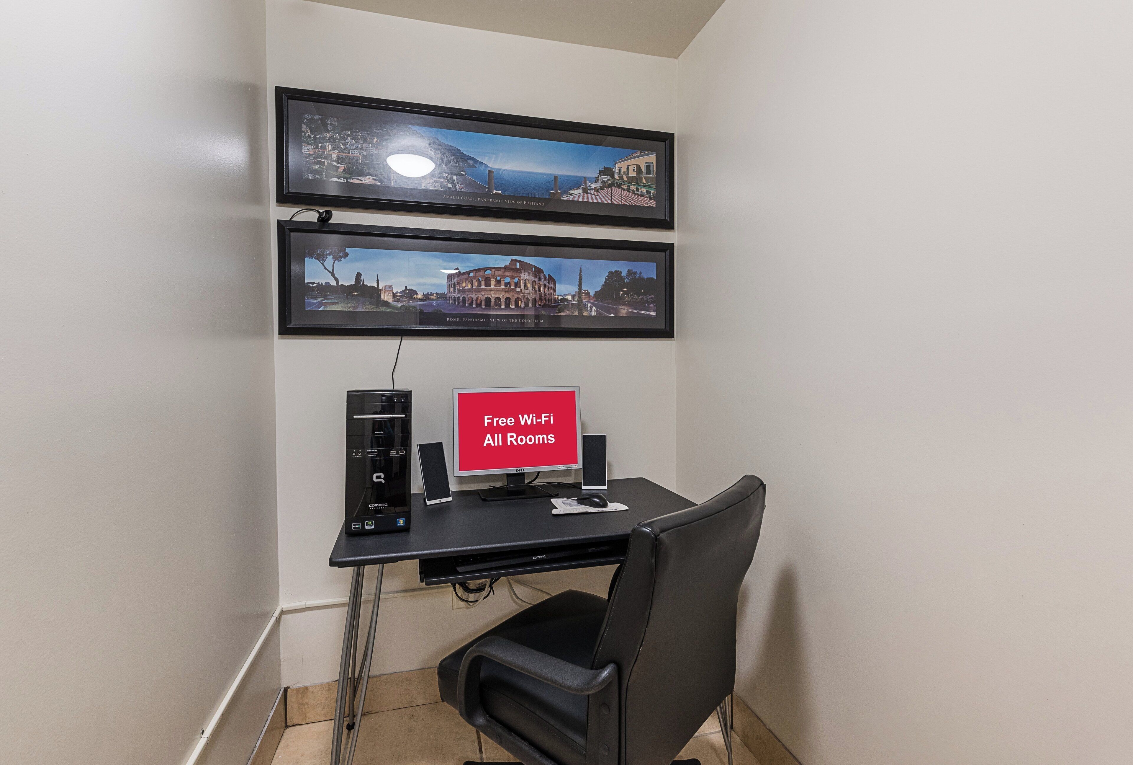 Ein Zimmer mit Schreibtisch, Computer und zwei gerahmten Panoramablicken an der Wand.