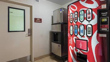 A hotel room with a minibar, a refrigerator, and a Coca-Cola branded beverage dispenser.