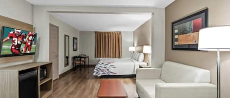 Una habitación de hotel con cama, sofá, televisor, escritorio y lámpara.