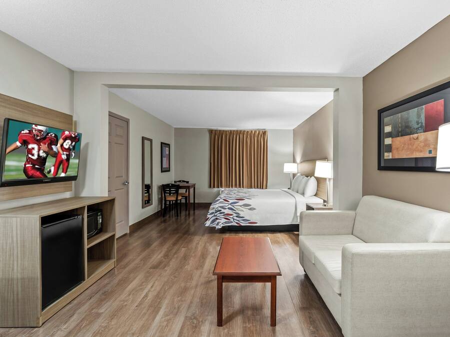 Una habitación de hotel con cama, sofá, televisor, escritorio y lámpara.