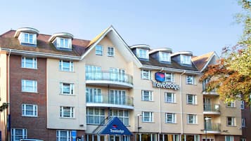 A Travelodge hotel with multiple balconies, a brick facade, and a parking area with cars.