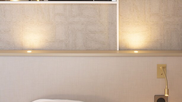 A hotel room with a bed, a wall-mounted mirror, and a bedside lamp. - Brit Hotel Nantes La Beaujoire Parc Expo (Nantes)