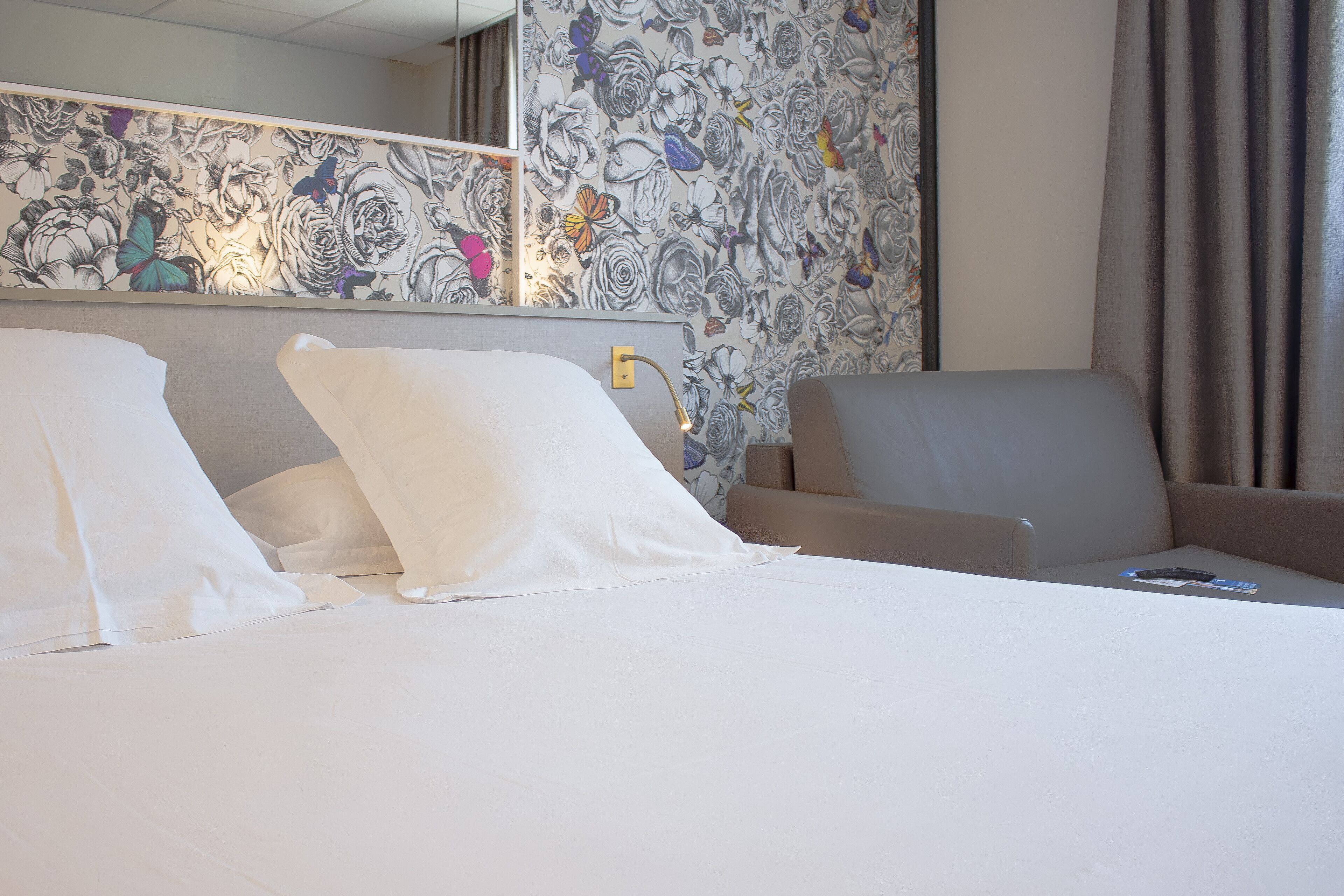 Una habitación de hotel con una cama, un sofá y un muro con papel tapiz floral.