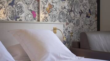 Una habitación de hotel con una cama bien hecha, un cabecero con detalles dorados y un diseño de papel tapiz floral.
