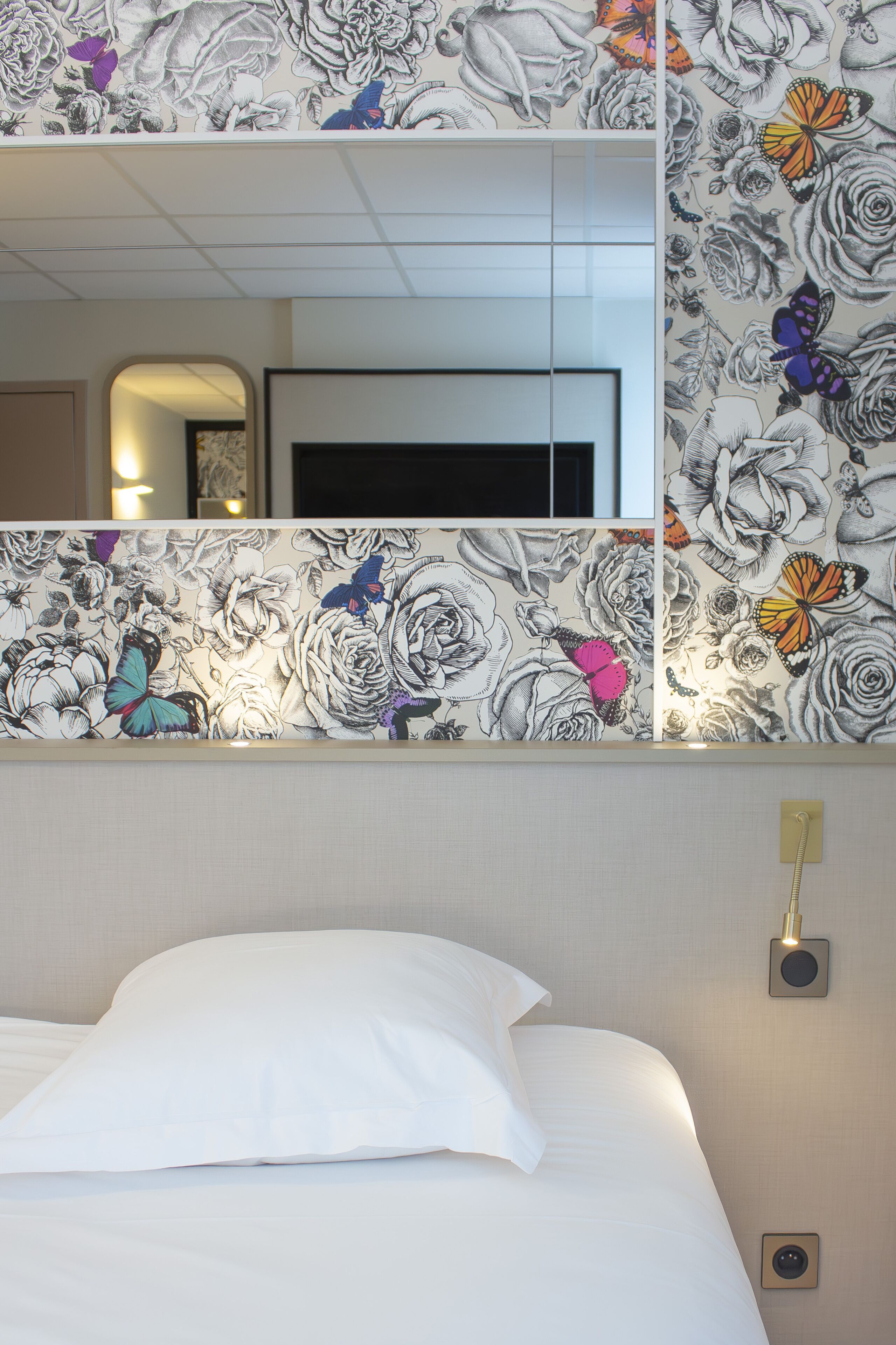 Een hotelkamer met een groot bed, een tv aan de muur en bloemenbehang.