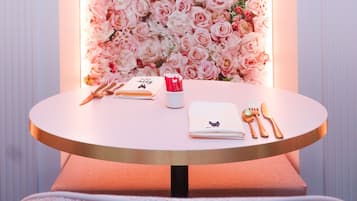 Una mesa con un fondo floral, un cuaderno, una taza roja y cubiertos.
