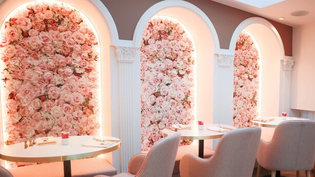 Une salle avec des tables et des chaises rondes, chaque table étant agrémentée d’un décor mural floral.