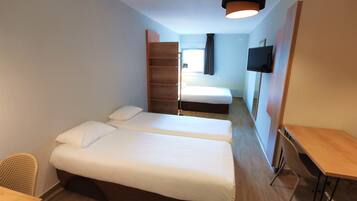 Een hotelkamer met twee bedden, een televisie, een bureau en een stoel.
