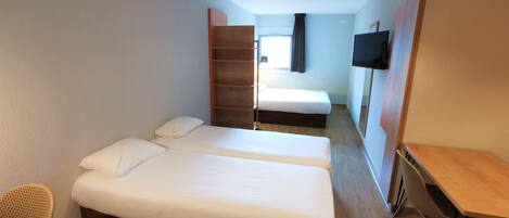 A hotel room with two beds, a TV, a desk, and a chair.