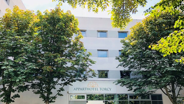 The exterior of the Apparthotel Torcy with a modern facade, large windows, and a glass entrance.