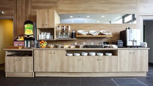 A modern kitchen with wooden cabinets, a coffee machine, and a fruit display.