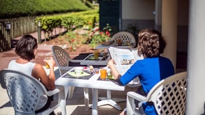 Two people seated at a table with a newspaper, a glass of orange juice, and a meal.