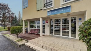 A building with a reception area, a bench, and a sign indicating 'L'ORÉE DU PARC'.