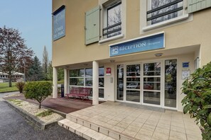 Rakennuksessa on vastaanottoaula, penkki ja kyltti, jossa lukee: »L’ORÉE DU PARC».